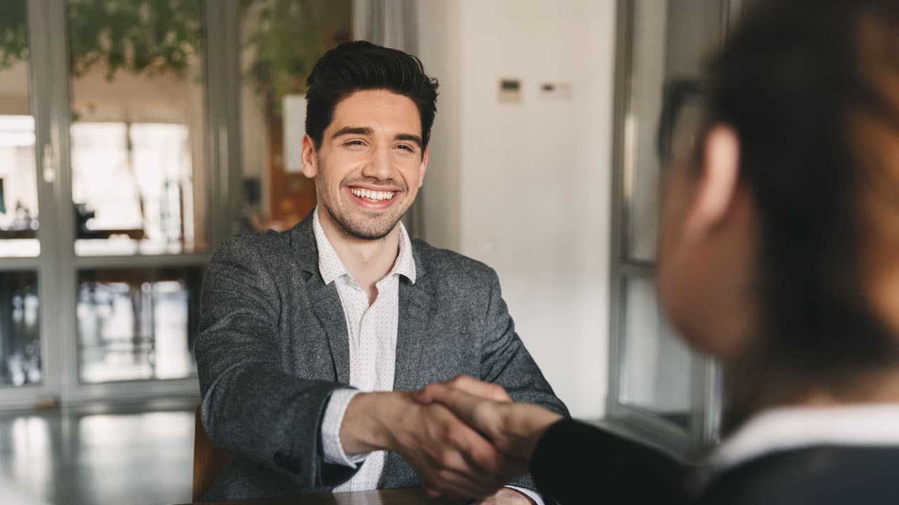 Man smiling shaking a woman's hand